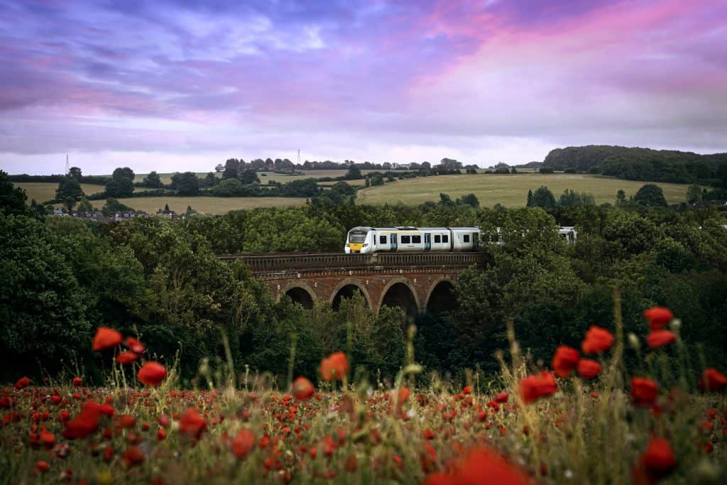 Thameslink train going across viaduct in green countryside
